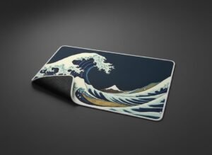 Great Wave XL Gaming Desk Mat shown at an angle on a dark studio background, white stitched edge and non-slip base visible